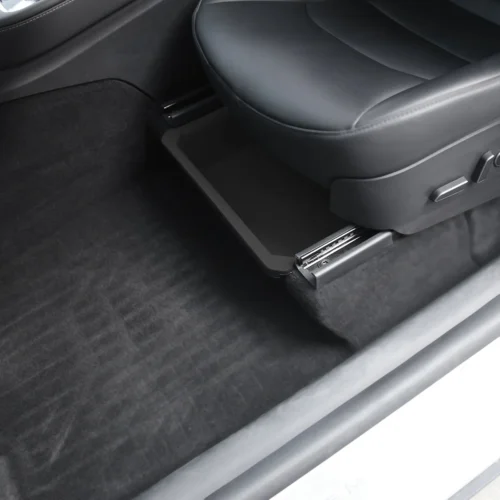Black plastic pull-out storage tray under a car seat in the footwell area