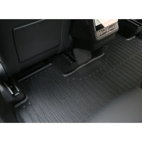 Rear passenger footwell showing a black ribbed rubber floor mat and part of the center console