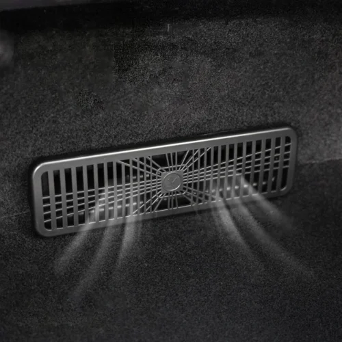 Rectangular vent grille in a car trunk with a central circular hub and radiating spokes behind it.