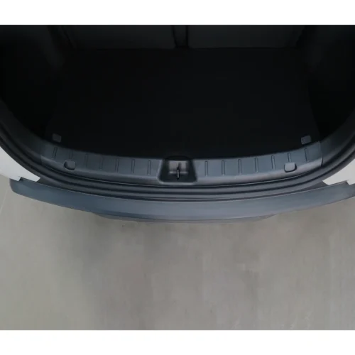 Open car trunk viewed from above, showing a black cargo area and the plastic trunk sill with a centered latch