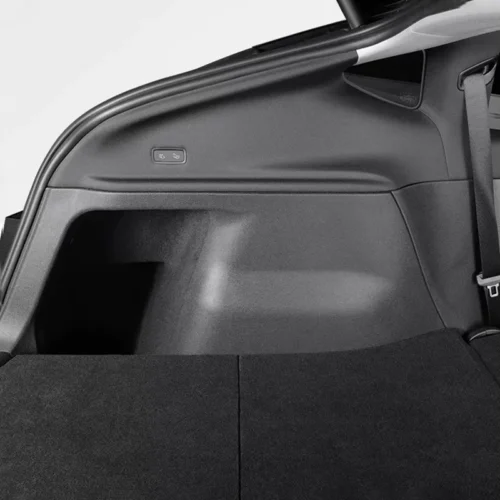 Close-up of a car's rear cargo area with the rear seats folded flat and a small control button on the side panel.
