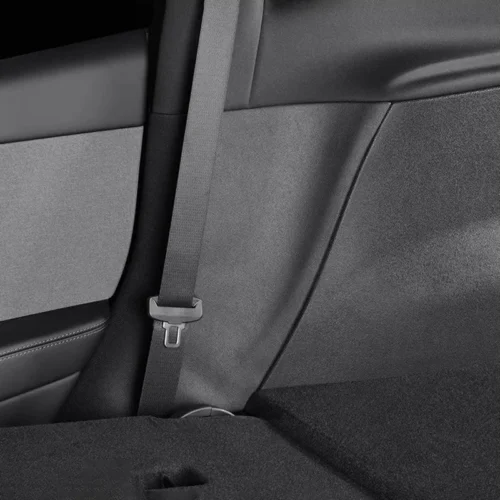 Rear passenger seat belt hanging with buckle in a dark car interior.