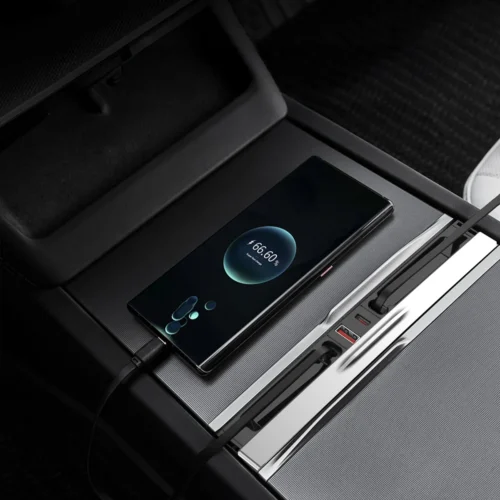 Smartphone charging on a wireless pad built into a car's center console with a cable connected to the side charger slot