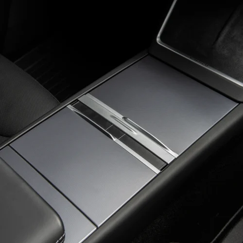 Center console in a luxury car showing a brushed metal sliding cover between textured panels.