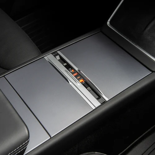 Center console of a luxury car with a sliding compartment open and orange illuminated controls