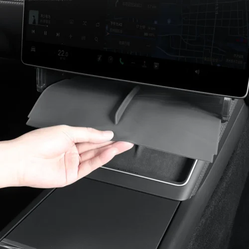 Hand pulling down a fold-out storage tray from the car's center console under the infotainment screen