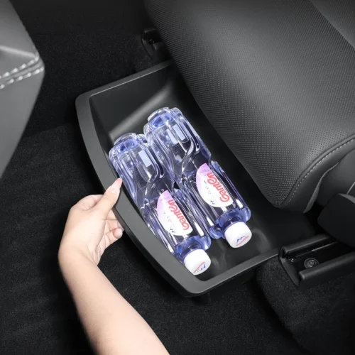 Person reaches to pull out a cup-holder tray in a car, revealing two blue water bottles inside