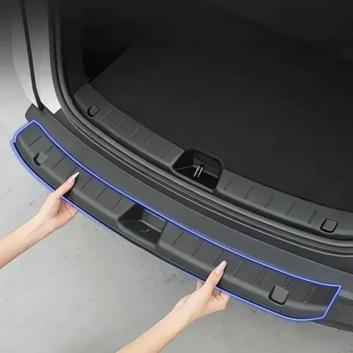 Person installs a blue-edged rear bumper protector along the trunk opening edge of a car.