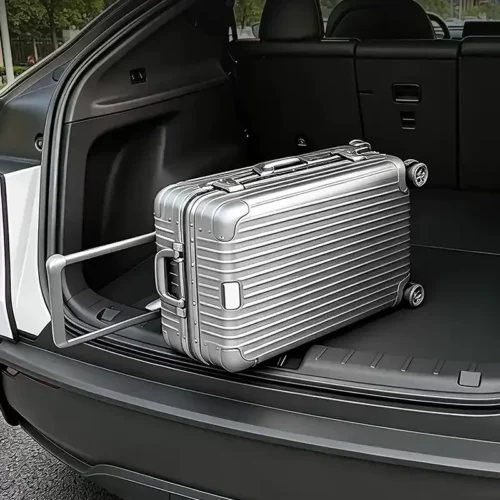 Silver hard-shell suitcase with wheels in the open trunk of an SUV.