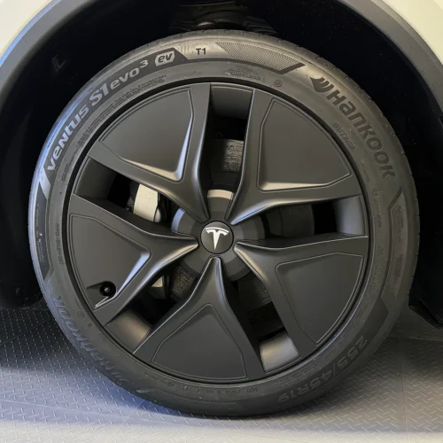 Tesla wheel with a matte black five-spoke rim and a Hankook tire, center cap displaying the Tesla logo