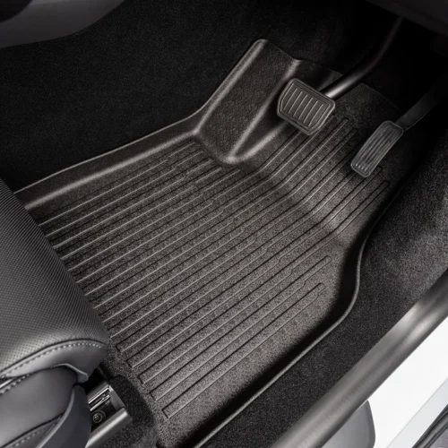 Driver's footwell with a textured rubber floor mat and two pedals (brake on left, accelerator on right).