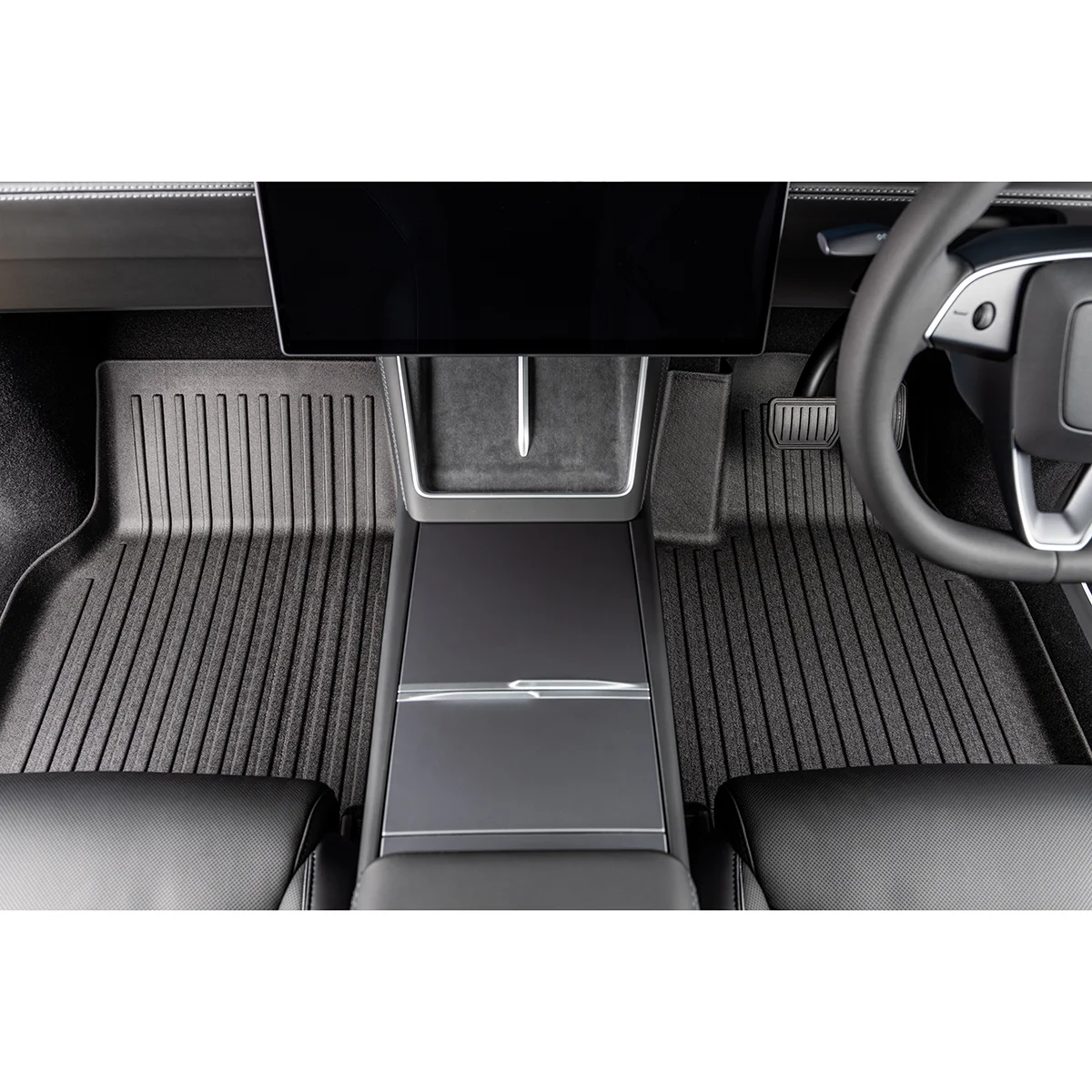Modern car interior featuring a large central touchscreen above the center console and ribbed floor mats on both sides of the aisle.
