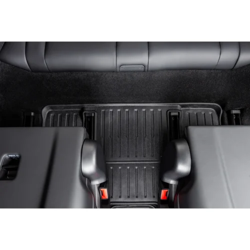 View of a car's rear seating area from above, showing a textured rubber floor mat and red-release seat belts on two seats
