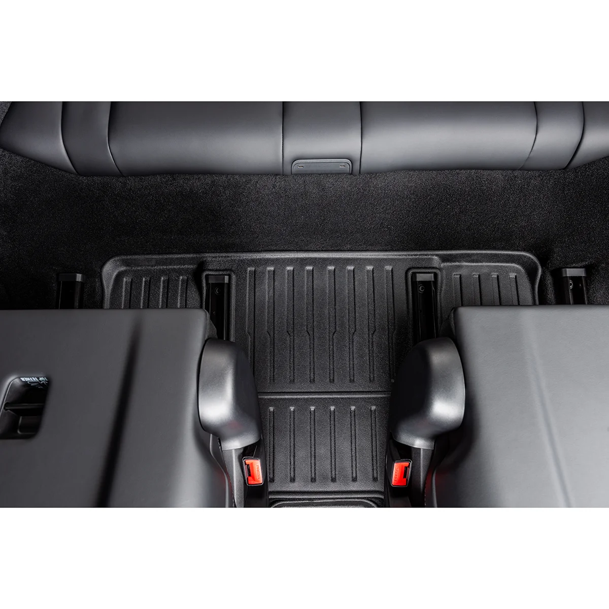 View of a car's rear seating area from above, showing a textured rubber floor mat and red-release seat belts on two seats