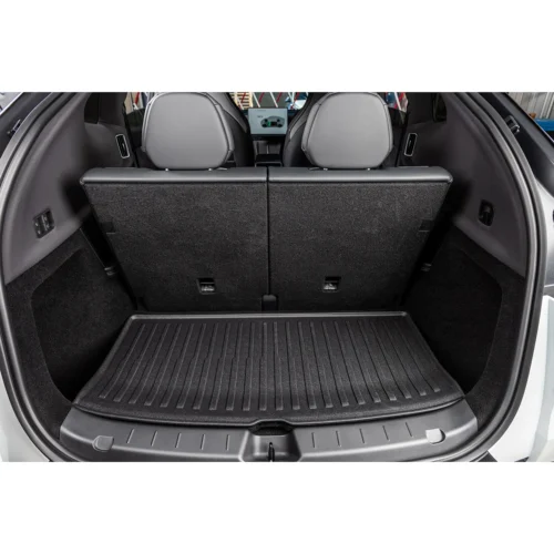 Cargo area of a hatchback with rear seats folded up and a ribbed rubber cargo mat in the trunk.