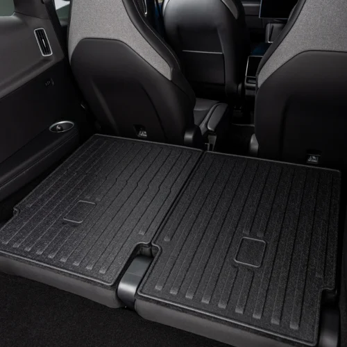 Rear seats folded down to create a flat, spacious cargo floor in a dark car interior with textured mats around it.