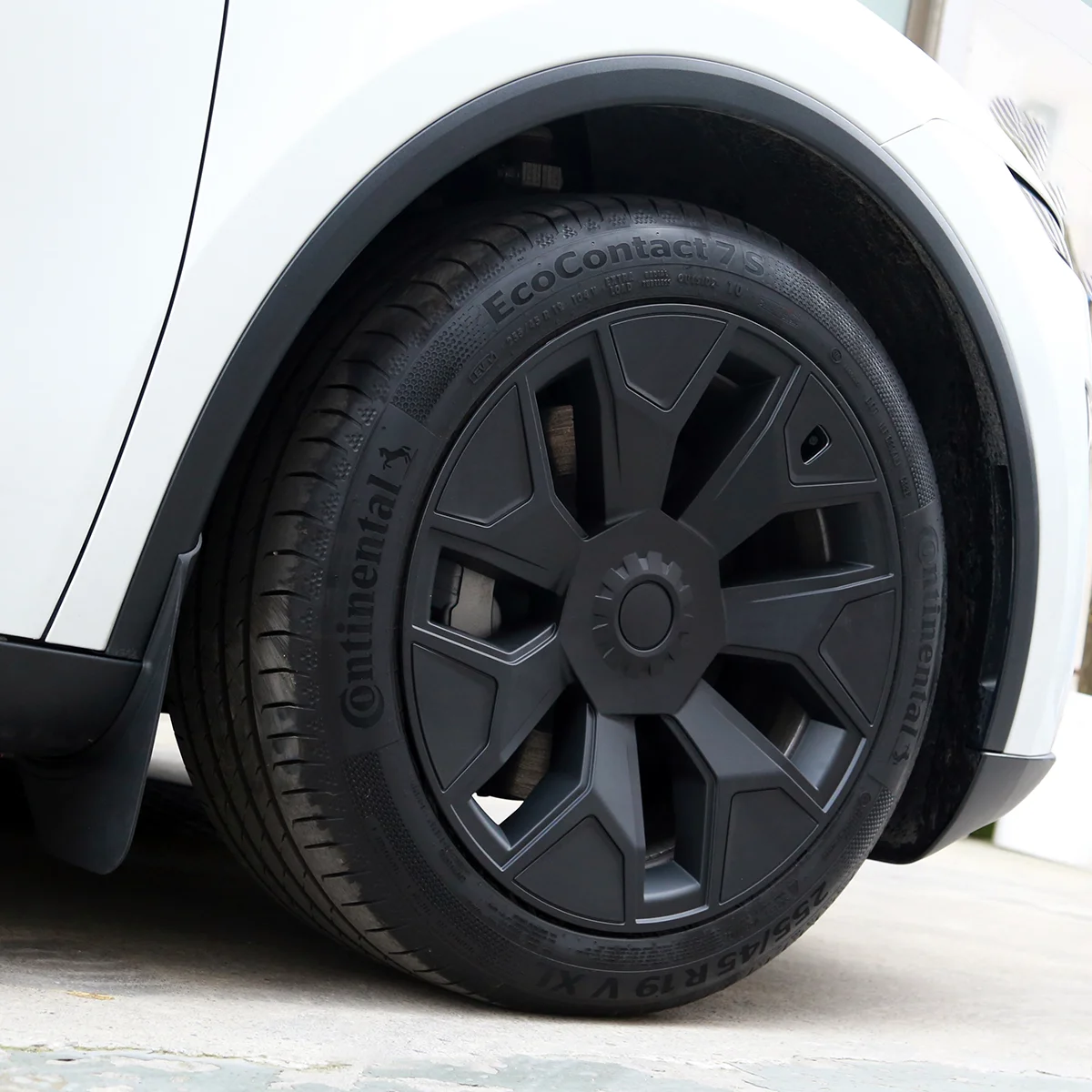 Close-up of a white car's wheel with a dark alloy rim and a Continental EcoContact 7S tire.