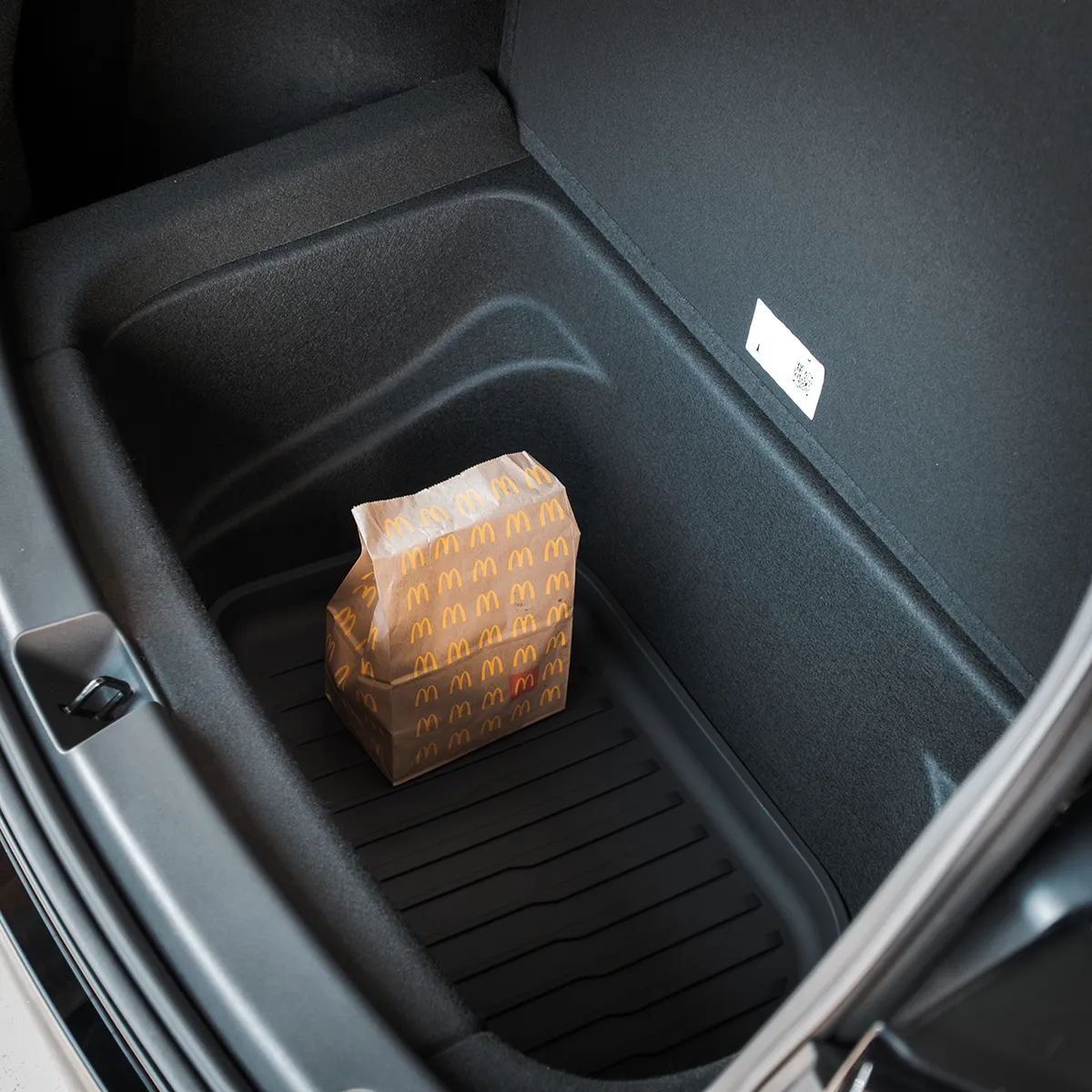 Small McDonald's takeout bag sits in the car's rear trunk storage tray.